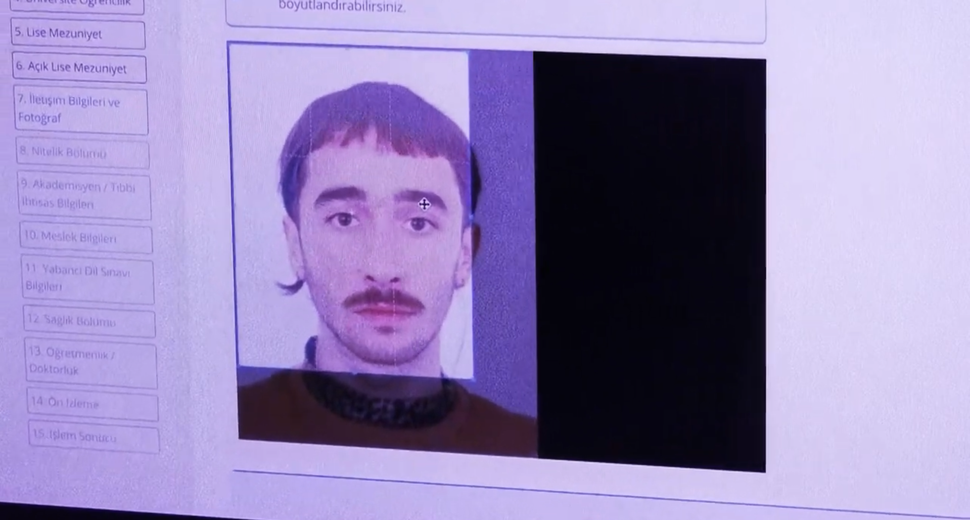 The image shows a digital interface, likely an official application portal, featuring a headshot of a person (Onur Tayranoğlu), with dark hair, a mustache, and a neutral expression. The photograph is being adjusted within a cropping tool on a computer screen, surrounded by a sidebar of numbered menu items in Turkish, related to education and personal information. The overall shot has the slight pixelation and cool-toned tint typical of a photo taken of a physical monitor.